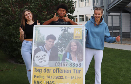 Zwei Schülerinnen und ein Schüler mit dem Plakat "Tag der offenen Tür"